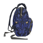 A blue and black damask-patterned backpack with gold-tone zippers and small tan accents, shown on a plain white background.